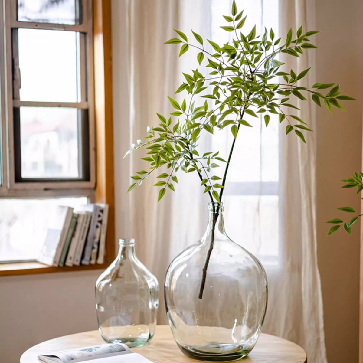 Clear glass vases with greenery on a table near a window
