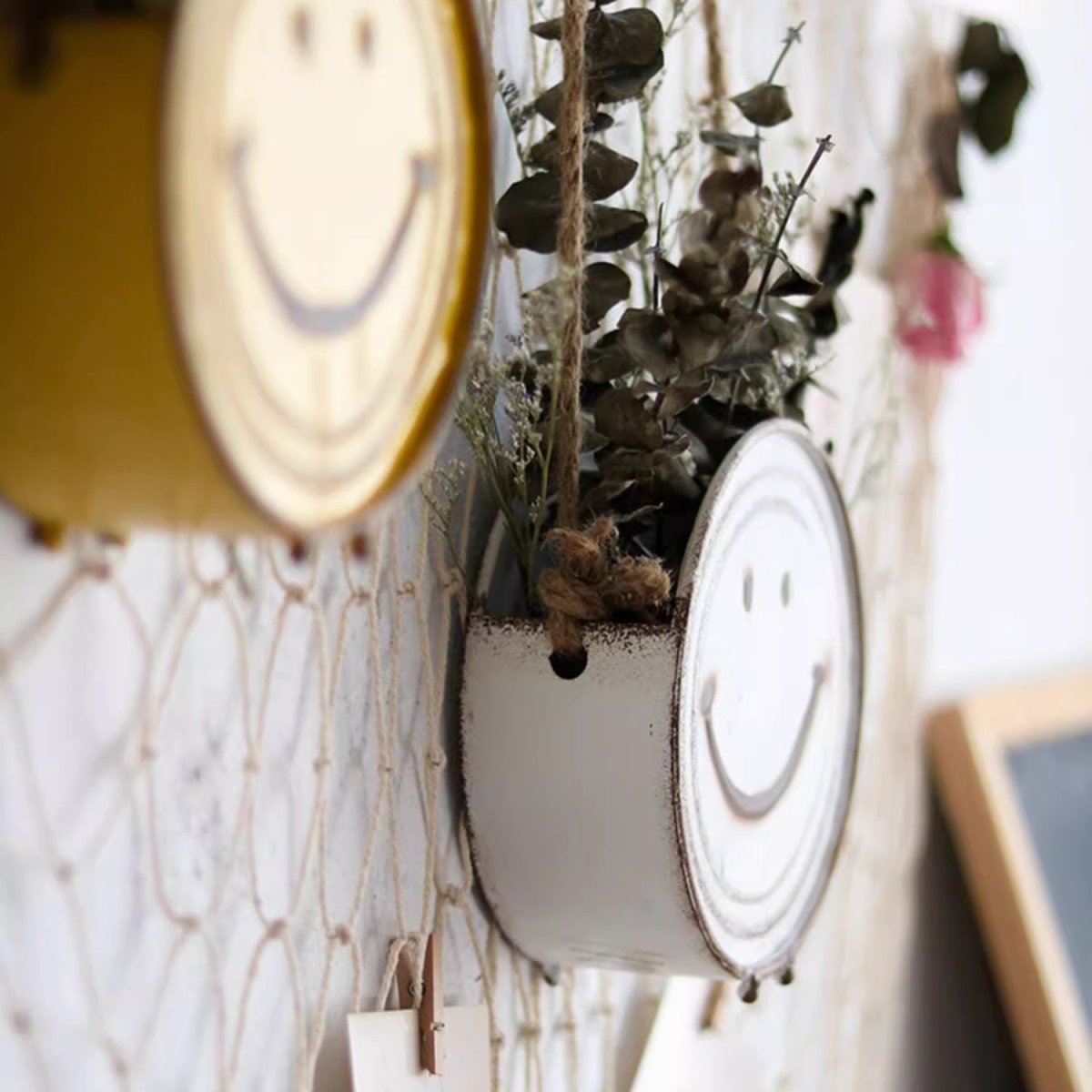 Decorative wall art with smiley face designs and a plant in a pot.