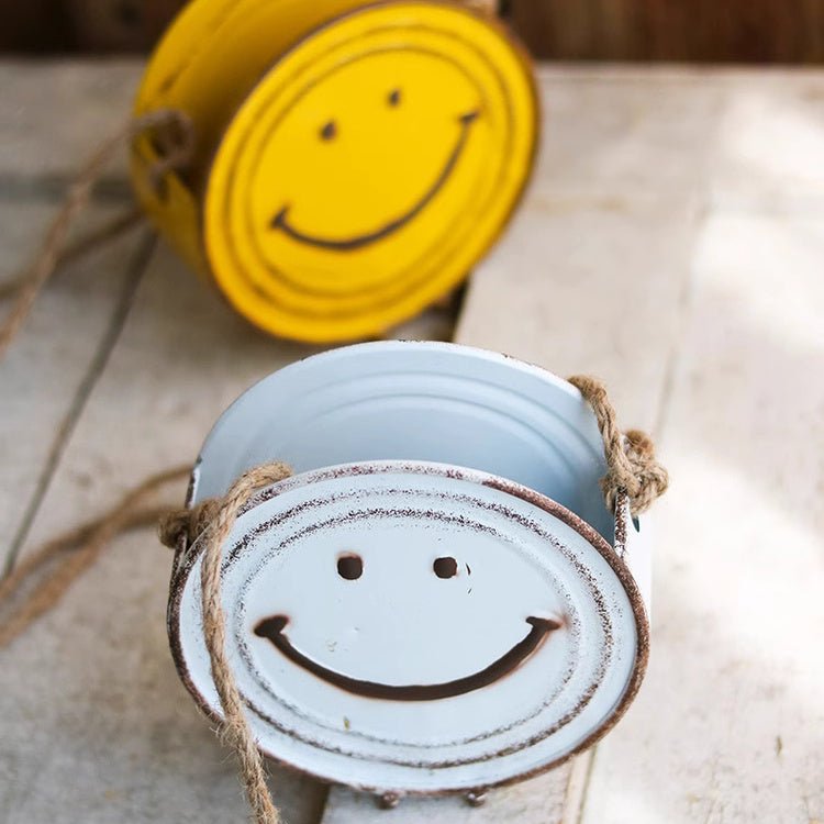 Two metal containers with smiley face designs on a textured surface.