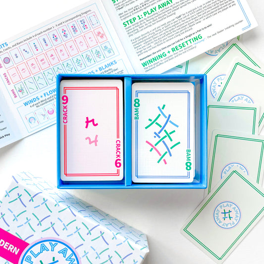 Mahjong Card game with cards open showing colorful designs and text, surrounded by game instructions on a white surface.