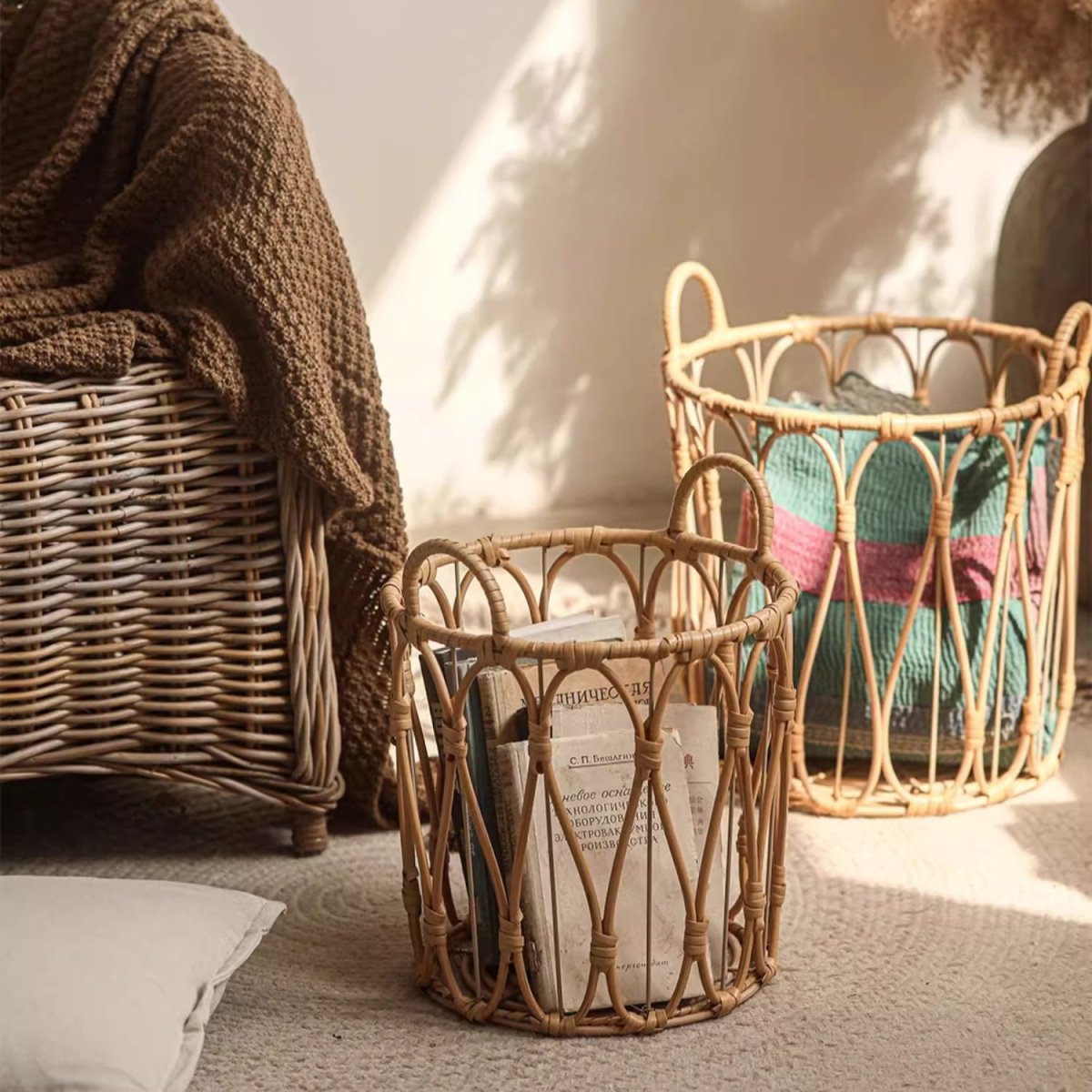 Wicker baskets with books and a blanket on a textured surface