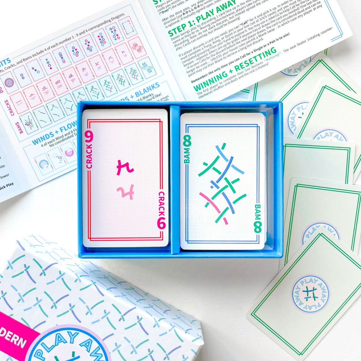 Mahjong Card game with cards open showing colorful designs and text, surrounded by game instructions on a white surface.