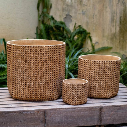 Three woven baskets of different sizes on a wooden surface with a natural background.