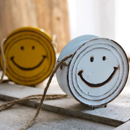 Two ceramic items with smiley face designs on a wooden surface.
